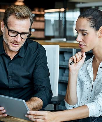 Integrate new members of the team more quickly  two colleagues looking at a tablet together