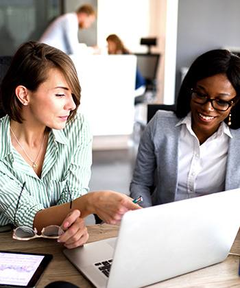 How does automation cut costs?  two women working on a laptop